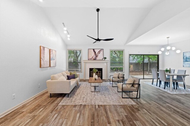 1706 Prairie Hen Cv, Austin, TX 78758 - living area with lofted ceiling, wood finished floors, a glass covered fireplace, plenty of natural light, and baseboards