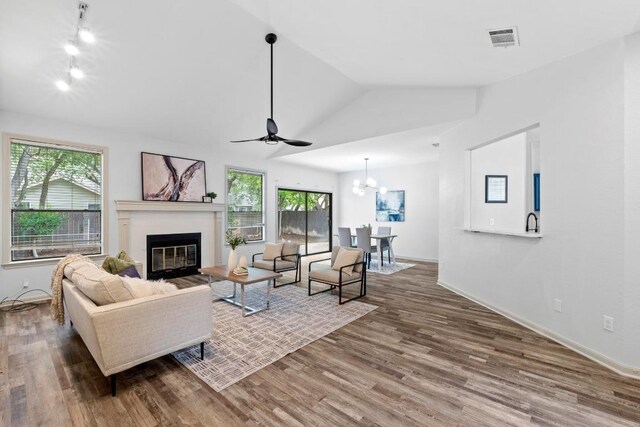 1706 Prairie Hen Cv, Austin, TX 78758 - living room featuring lofted ceiling, a glass covered fireplace, a ceiling fan, wood finished floors, and a chandelier
