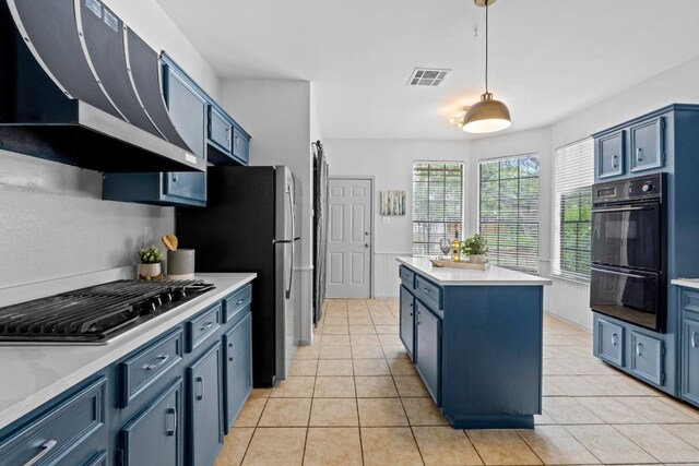 1706 Prairie Hen Cv, Austin, TX 78758 - kitchen featuring appliances with stainless steel finishes, range hood, light countertops, a center island, and blue cabinetry