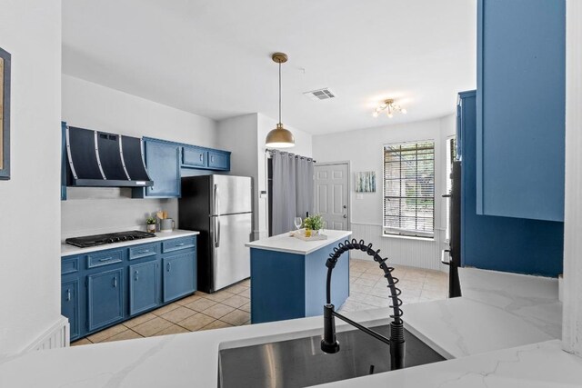 1706 Prairie Hen Cv, Austin, TX 78758 - kitchen with freestanding refrigerator, blue cabinets, range hood, gas stovetop, and a kitchen island