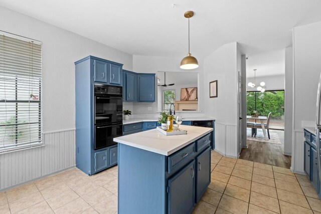 1706 Prairie Hen Cv, Austin, TX 78758 - kitchen featuring blue cabinets, light countertops, wainscoting, a kitchen island, and light tile patterned floors