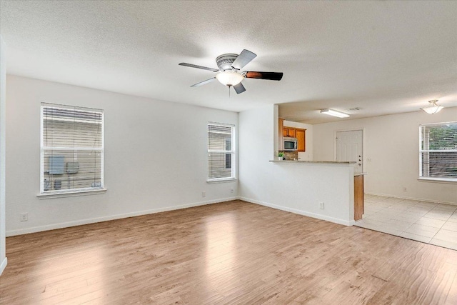 8520 Chick Pea Ln, Austin, TX 78748 - unfurnished living room featuring light wood-style floors, ceiling fan, a textured ceiling, and baseboards