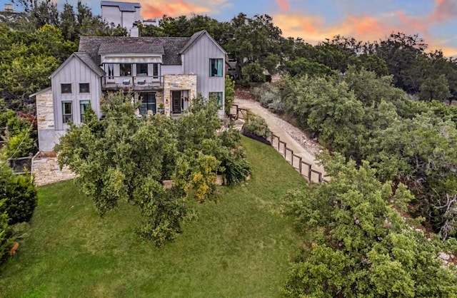 19506 Inverness Dr, Lakeway, TX 78669 - back of house at dusk featuring board and batten siding, a balcony, and stone siding