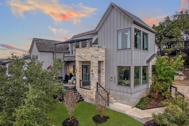 19506 Inverness Dr, Lakeway, TX 78669 - modern home featuring a balcony, stone siding, board and batten siding, a yard, and a shingled roof