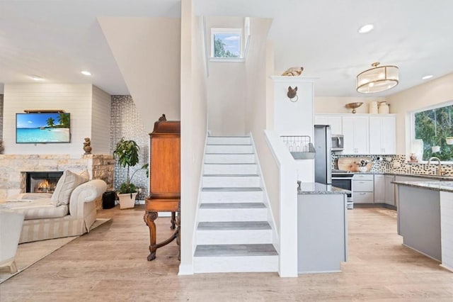 19506 Inverness Dr, Lakeway, TX 78669 - staircase featuring wood finished floors, a stone fireplace, and recessed lighting