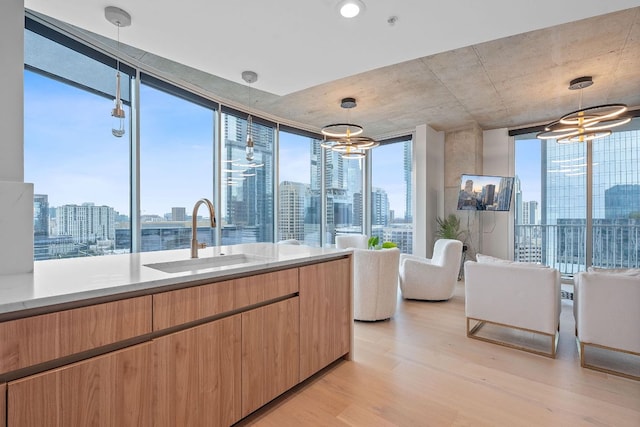 360 Nueces St Unit 1811, Austin, TX 78701 - kitchen featuring a chandelier, a sink, light wood finished floors, a wall of windows, and pendant lighting