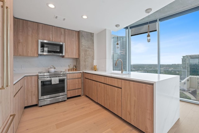 360 Nueces St Unit 1811, Austin, TX 78701 - kitchen with stainless steel appliances, a sink, light countertops, a peninsula, and light wood-type flooring