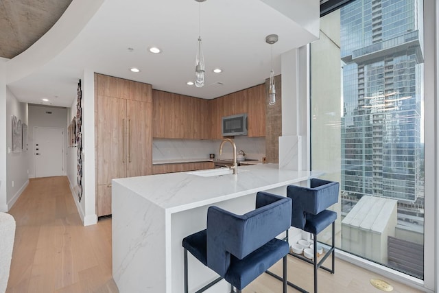360 Nueces St Unit 1811, Austin, TX 78701 - kitchen with a sink, modern cabinets, brown cabinetry, stainless steel microwave, and a peninsula