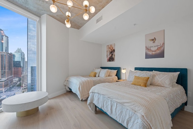 360 Nueces St Unit 1811, Austin, TX 78701 - bedroom featuring wood finished floors, a chandelier, baseboards, a view of skyline, and a wall of windows