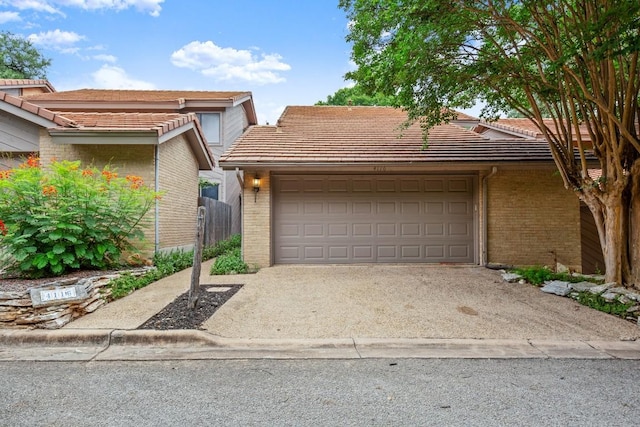 4116 Creek Ledge Unit 108, Austin, TX 78731 - view of front of house with a tile roof, brick siding, concrete driveway, and an attached garage