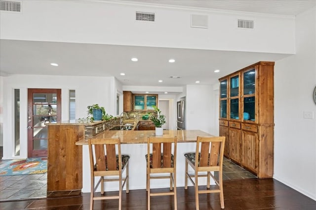 922 Challenger, Lakeway, TX 78734 - kitchen featuring stainless steel fridge, recessed lighting, a kitchen bar, a peninsula, and brown cabinetry