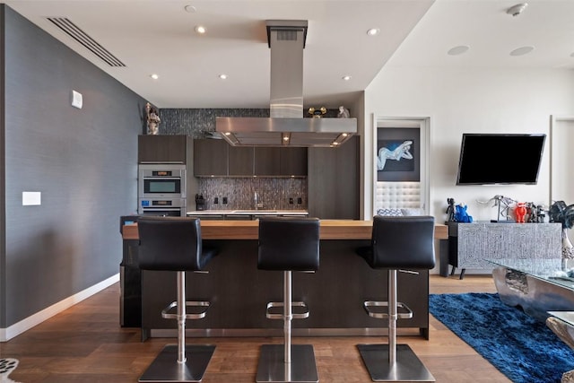 210 Lavaca St Unit 2203, Austin, TX 78701 - kitchen with island exhaust hood, modern cabinets, a breakfast bar, light wood-type flooring, and butcher block countertops