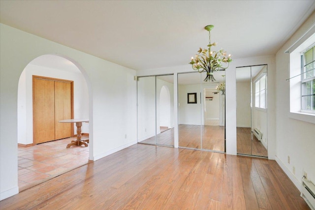 9438 Circle Dr, Austin, TX 78736 - unfurnished bedroom with multiple closets, arched walkways, a chandelier, and light wood-type flooring