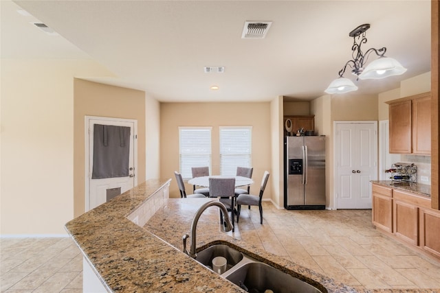 107 Marklawn Ln, Hutto, TX 78634 - kitchen with stainless steel fridge, decorative light fixtures, and light stone counters