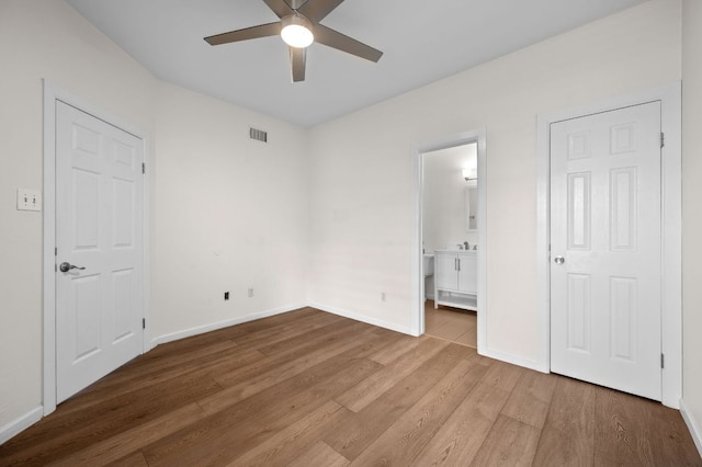 12166 Metric Blvd Unit 115, Austin, TX 78758 - unfurnished bedroom featuring wood finished floors, ensuite bath, and ceiling fan