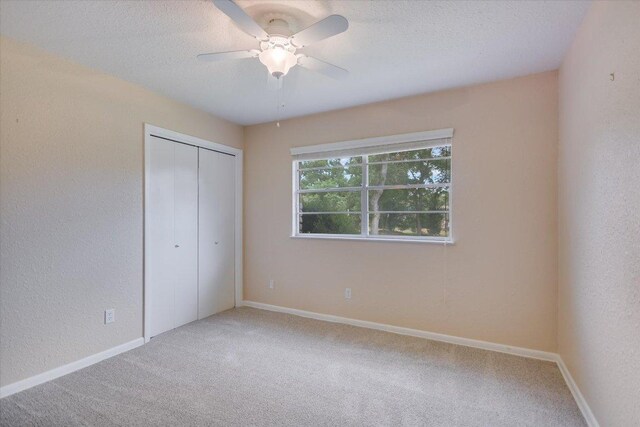 9504 Flintrock Cir, Austin, TX 78737 - unfurnished bedroom featuring carpet flooring, a textured ceiling, a closet, baseboards, and ceiling fan