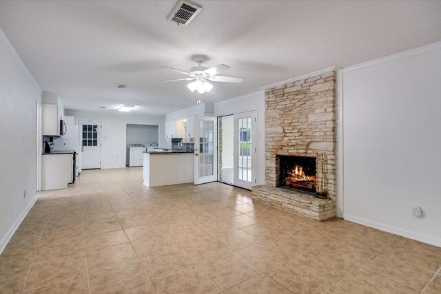 9504 Flintrock Cir, Austin, TX 78737 - unfurnished living room with ornamental molding, a ceiling fan, a stone fireplace, light tile patterned floors, and washer / dryer