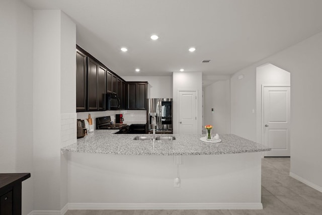 13712 Fallsprings Way, Manor, TX 78653 - kitchen featuring black microwave, stove, a sink, stainless steel refrigerator with ice dispenser, and a peninsula