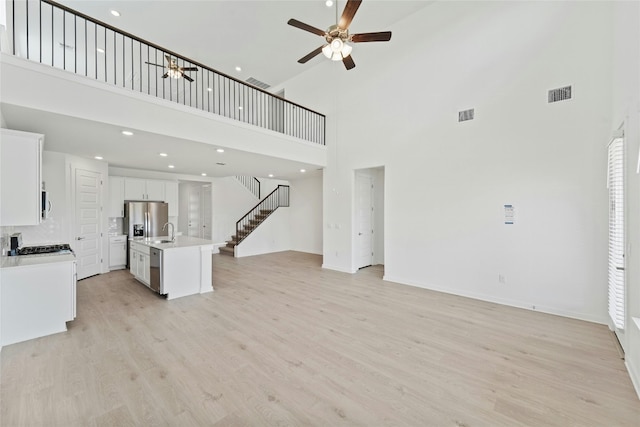 632 Deerpath St, Leander, TX 78641 - unfurnished living room with a high ceiling, a sink, ceiling fan, stairway, and light wood-type flooring