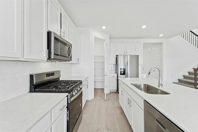 632 Deerpath St, Leander, TX 78641 - kitchen with appliances with stainless steel finishes, a sink, light wood finished floors, white cabinetry, and recessed lighting