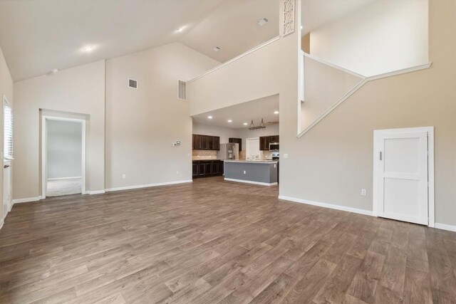 1008 Comal Run, Hutto, TX 78634 - unfurnished living room with high vaulted ceiling, wood finished floors, and baseboards