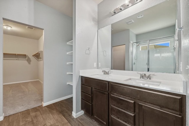1008 Comal Run, Hutto, TX 78634 - full bathroom featuring a spacious closet, double vanity, wood finished floors, a stall shower, and baseboards