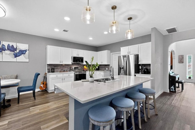 952 Hometown Pkwy, Kyle, TX 78640 - kitchen with stainless steel appliances, a kitchen bar, wood finished floors, backsplash, and recessed lighting