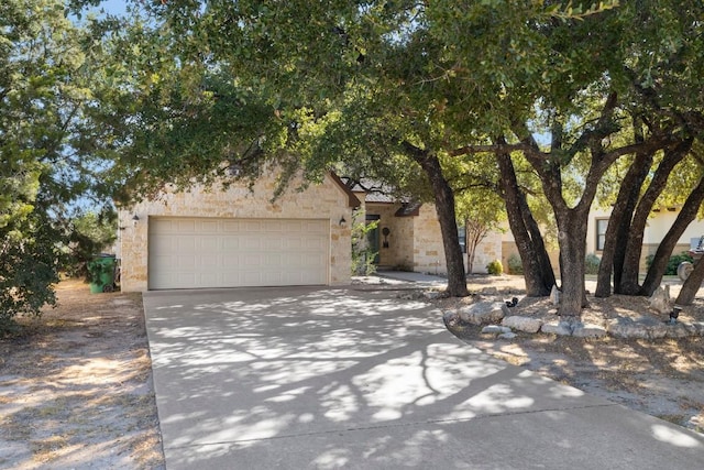 15100 General Williamson Dr, Austin, TX 78734 - view of property hidden behind natural elements featuring driveway, an attached garage, and stone siding