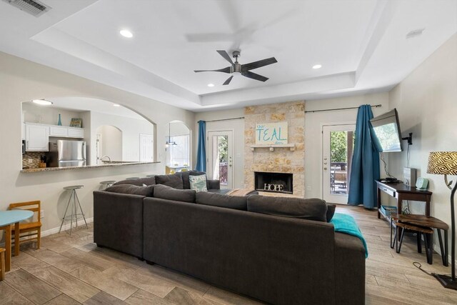 15100 General Williamson Dr, Austin, TX 78734 - living area featuring a tray ceiling, a ceiling fan, arched walkways, recessed lighting, and a stone fireplace