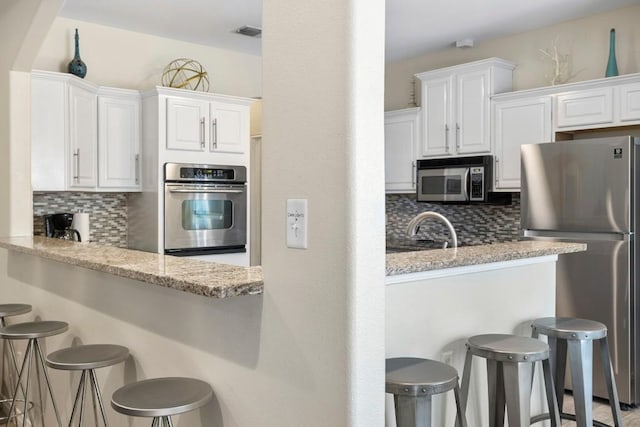 15100 General Williamson Dr, Austin, TX 78734 - kitchen featuring stainless steel appliances, decorative backsplash, and a breakfast bar area
