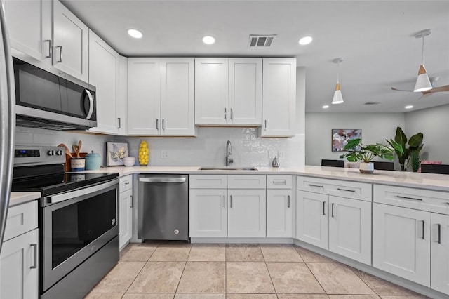 7065 Wheatfield Way, Kyle, TX 78640 - kitchen featuring appliances with stainless steel finishes, light countertops, tasteful backsplash, white cabinets, and pendant lighting