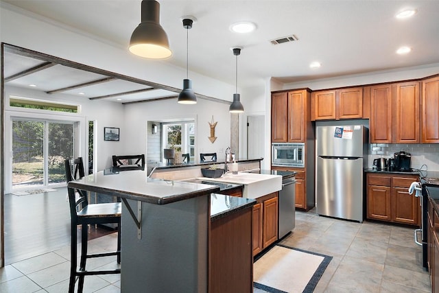 415 Angel Fire Rd, Dripping Springs, TX 78620 - kitchen with stainless steel appliances, brown cabinetry, a spacious island, plenty of natural light, and recessed lighting