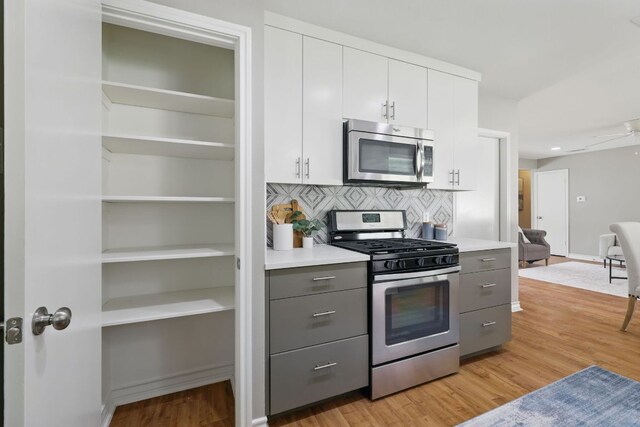 8506 Shenandoah Dr, Austin, TX 78753 - kitchen with appliances with stainless steel finishes, gray cabinets, light wood-type flooring, white cabinetry, and decorative backsplash