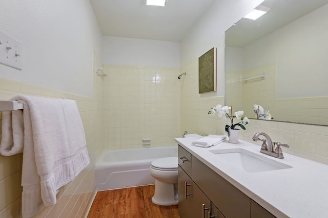 8506 Shenandoah Dr, Austin, TX 78753 - bathroom featuring wood finished floors, tile walls, vanity, toilet, and shower / bathtub combination