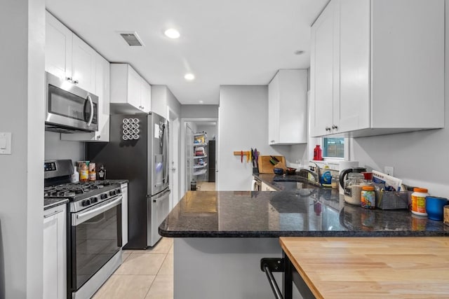 5205 Buffalo Pass, Austin, TX 78745 - kitchen featuring stainless steel appliances, a sink, white cabinets, dark stone countertops, and recessed lighting