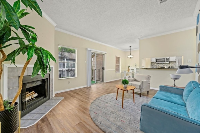 12166 Metric Blvd Bldg 10Unit Unit 246, Austin, TX 78758 - living room featuring light wood-style flooring, ornamental molding, a fireplace, baseboards, and a textured ceiling