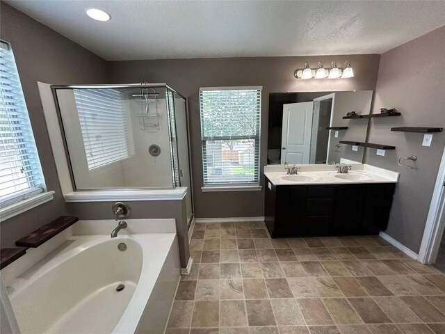 125 Lilly Crk, Boerne, TX 78006 - bathroom featuring a bath, double vanity, a shower stall, baseboards, and a textured ceiling