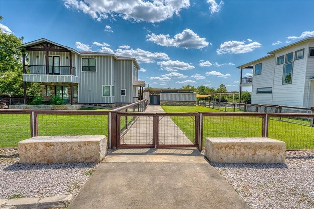 view of front of house with board and batten siding, a gate, and a balcony