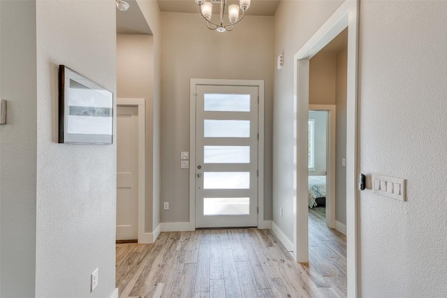 entrance foyer featuring wood finished floors, a chandelier, and baseboards