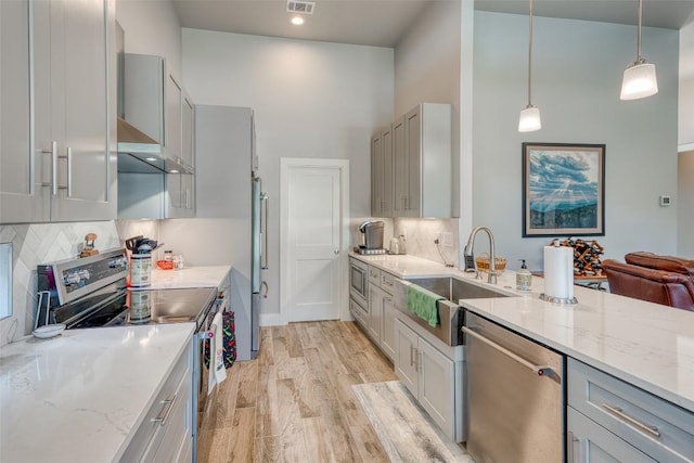 kitchen featuring appliances with stainless steel finishes, a sink, gray cabinets, a towering ceiling, and recessed lighting