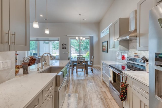 kitchen featuring stainless steel range with electric cooktop, wall chimney range hood, light wood-style flooring, tasteful backsplash, and light stone counters