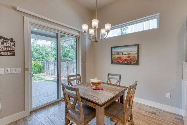 dining room featuring healthy amount of natural light, light wood-type flooring, a chandelier, and baseboards