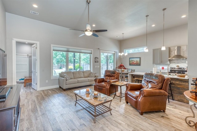 living room featuring light wood finished floors, ceiling fan, recessed lighting, baseboards, and a chandelier