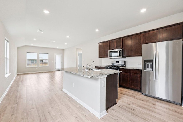 136 Ellinger Rd, Georgetown, TX 78626 - kitchen featuring appliances with stainless steel finishes, a sink, light wood-type flooring, dark brown cabinetry, and light stone countertops