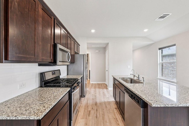 136 Ellinger Rd, Georgetown, TX 78626 - kitchen with a sink, stainless steel appliances, light wood-style floors, a kitchen island with sink, and backsplash