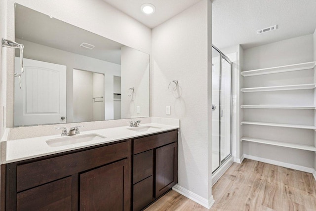 136 Ellinger Rd, Georgetown, TX 78626 - bathroom featuring wood finished floors, a shower stall, double vanity, and baseboards