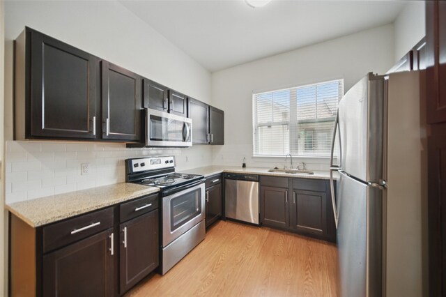 2400 Louis Henna Blvd Unit 106, Round Rock, TX 78664 - kitchen featuring stainless steel appliances, light wood-style floors, backsplash, and light stone counters