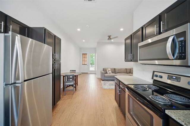 2400 Louis Henna Blvd Unit 106, Round Rock, TX 78664 - kitchen with appliances with stainless steel finishes, light wood finished floors, tasteful backsplash, dark cabinets, and open floor plan