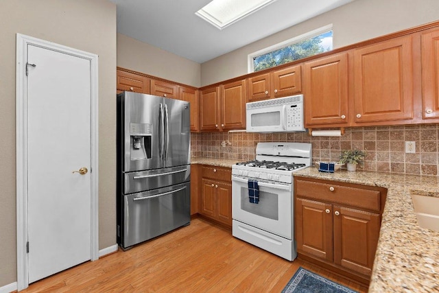 206 Whispering Wind Dr, Georgetown, TX 78633 - kitchen with white appliances, light wood-style flooring, backsplash, and brown cabinetry