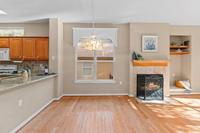 206 Whispering Wind Dr, Georgetown, TX 78633 - kitchen with white appliances, light wood-style floors, a chandelier, light stone counters, and backsplash